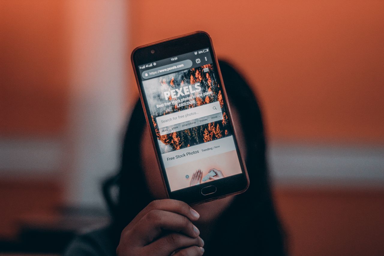 Close-up of a woman browsing Pexels website on a smartphone, indoors.